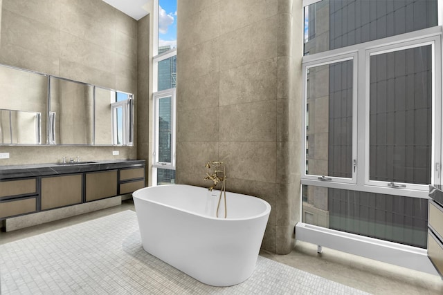 full bathroom with vanity, a soaking tub, and tile walls