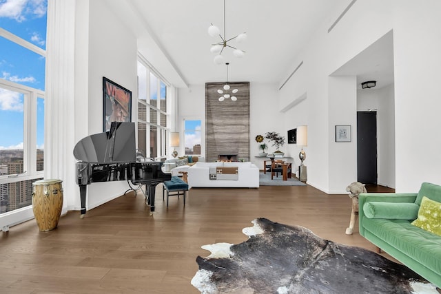 living room featuring a fireplace, a high ceiling, baseboards, and wood finished floors