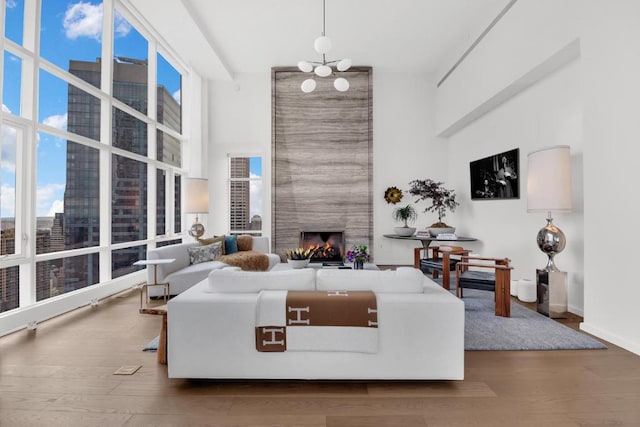 living room featuring hardwood / wood-style floors, a large fireplace, and an inviting chandelier