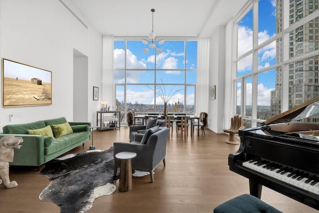 interior space featuring a towering ceiling, hardwood / wood-style flooring, expansive windows, and a notable chandelier