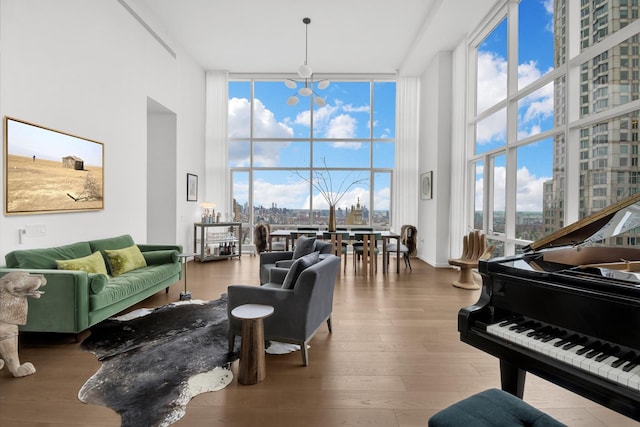 living room featuring wood finished floors, a high ceiling, expansive windows, a city view, and a notable chandelier