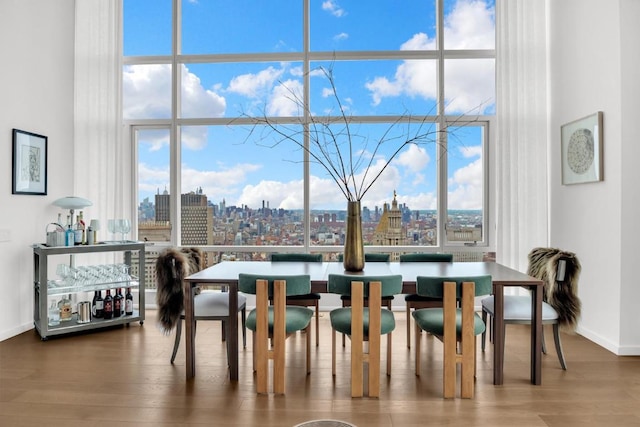 dining area with wood-type flooring, a high ceiling, and a wealth of natural light