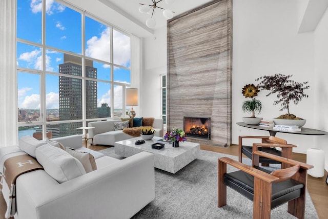 living room featuring a premium fireplace, a towering ceiling, wood-type flooring, and a notable chandelier