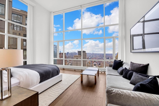 bedroom featuring a city view, hardwood / wood-style flooring, and expansive windows