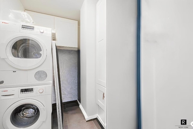 laundry area featuring stacked washer and clothes dryer and dark tile patterned floors