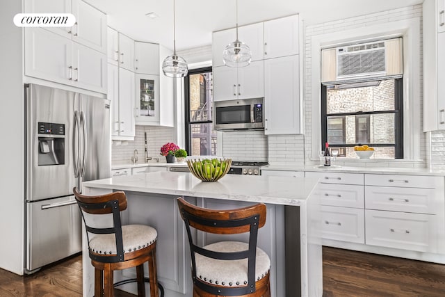 kitchen with hanging light fixtures, a breakfast bar, white cabinets, and appliances with stainless steel finishes