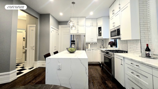 kitchen with white cabinetry, appliances with stainless steel finishes, a center island, and light stone counters