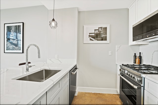 kitchen featuring light stone counters, a sink, hanging light fixtures, stainless steel appliances, and baseboards