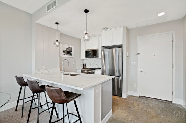 kitchen with sink, hanging light fixtures, a kitchen breakfast bar, stainless steel appliances, and white cabinets