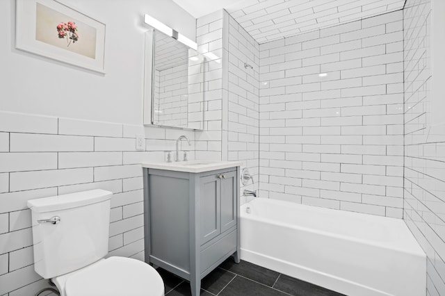 full bathroom with toilet, tiled shower / bath combo, tile walls, tile patterned floors, and vanity