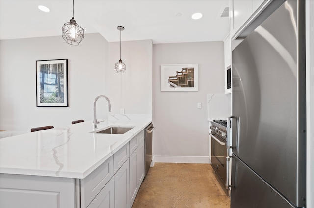 kitchen featuring concrete floors, a sink, appliances with stainless steel finishes, a peninsula, and light stone counters