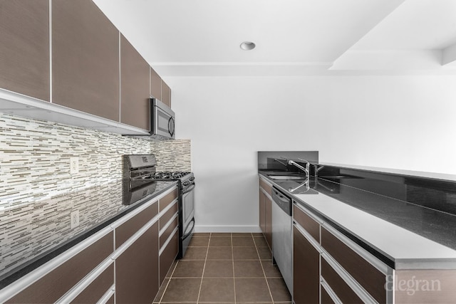 kitchen featuring sink, dark tile patterned floors, dark brown cabinets, stainless steel appliances, and tasteful backsplash