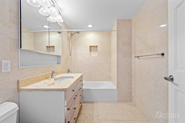 full bathroom with vanity, tiled shower / bath, tile walls, and toilet