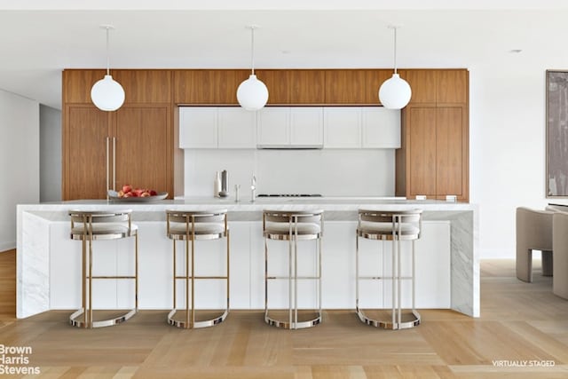 kitchen featuring a kitchen bar, light parquet floors, and white cabinets