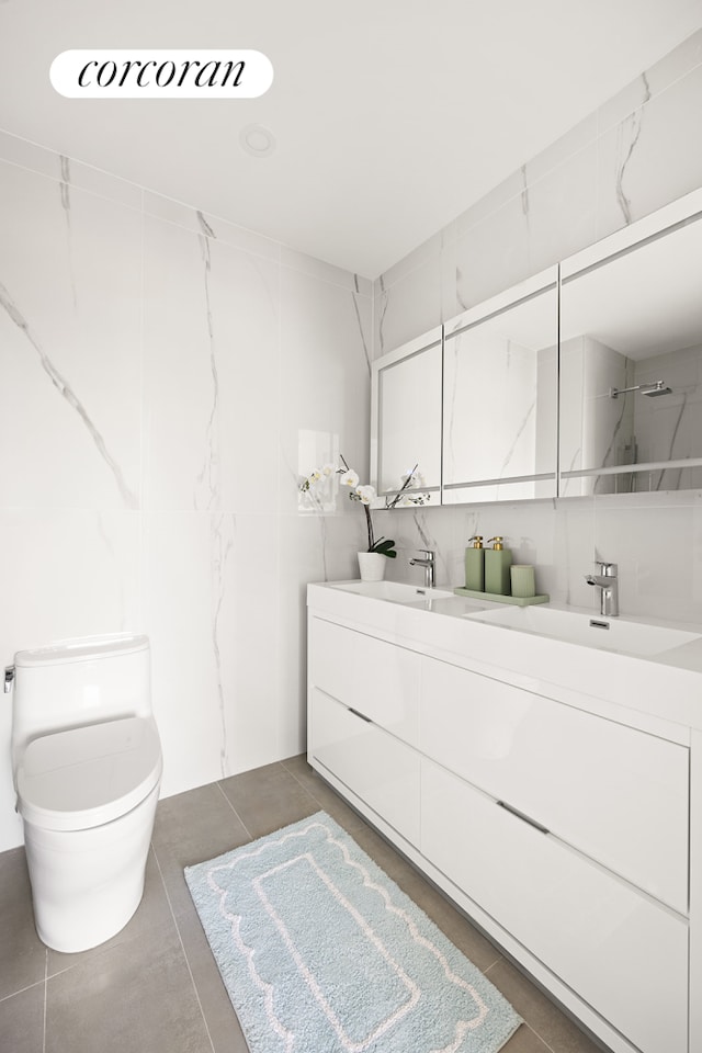 full bath with double vanity, a sink, toilet, and tile patterned floors