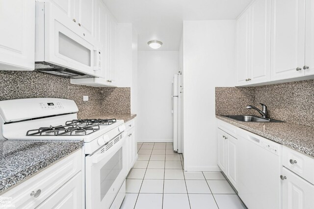 kitchen with a sink, white appliances, white cabinets, and light tile patterned floors