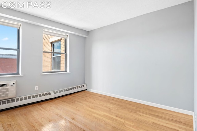 empty room featuring light hardwood / wood-style floors and a baseboard heating unit