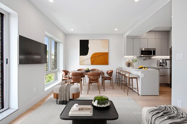 living room featuring light wood finished floors, baseboards, and recessed lighting