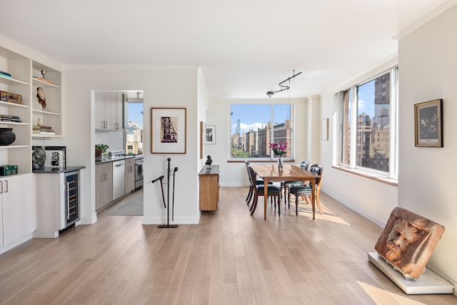 dining area with light wood-type flooring, beverage cooler, and ornamental molding