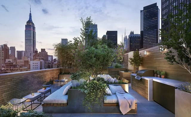 patio terrace at dusk featuring a grill and exterior kitchen