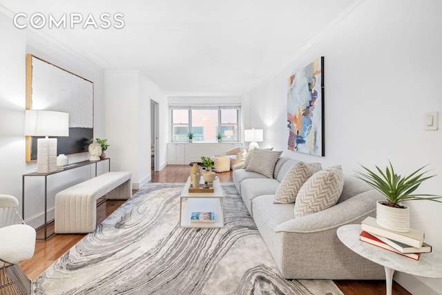 living area with crown molding, wood finished floors, and baseboards