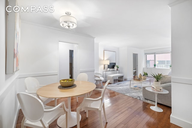 dining area with ornamental molding and hardwood / wood-style flooring