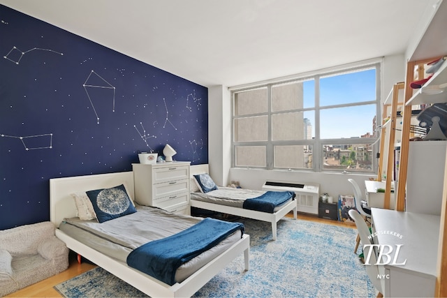 bedroom featuring hardwood / wood-style floors and a wall mounted AC