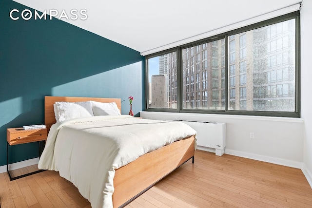 bedroom with radiator heating unit and light hardwood / wood-style floors