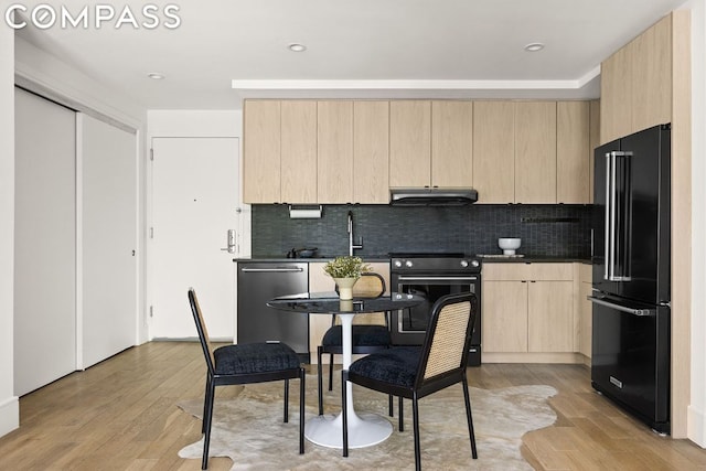 kitchen with black appliances, light brown cabinetry, tasteful backsplash, and light hardwood / wood-style floors