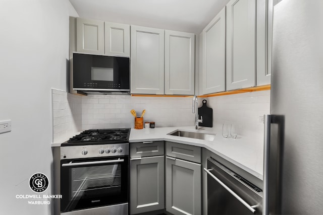 kitchen featuring gray cabinetry, sink, tasteful backsplash, and appliances with stainless steel finishes