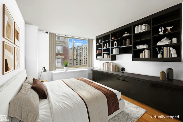 bedroom featuring a city view and wood finished floors