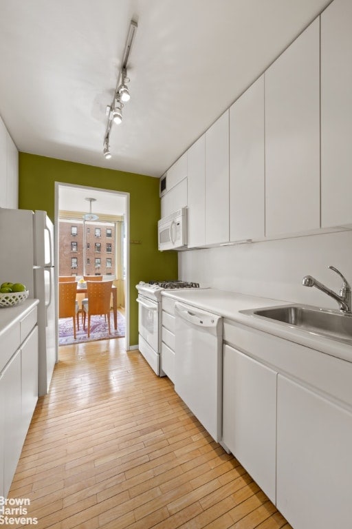 kitchen featuring white cabinetry, sink, white appliances, and light hardwood / wood-style floors