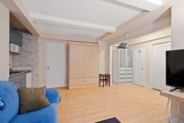 living area with light wood-style floors and beam ceiling