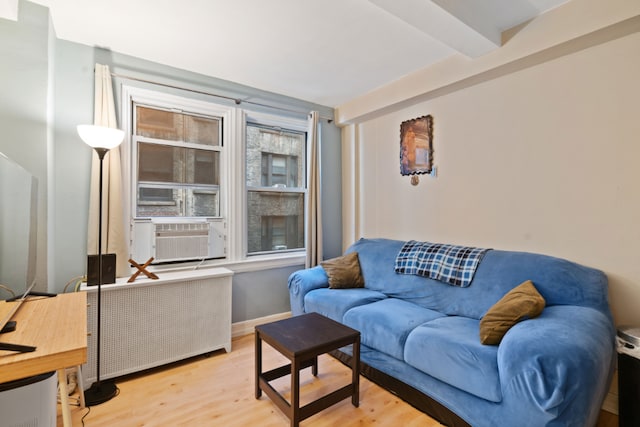 living room featuring beamed ceiling, radiator heating unit, light hardwood / wood-style floors, and cooling unit