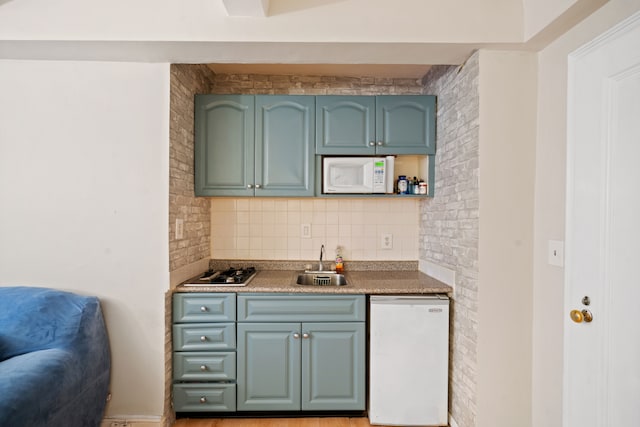 kitchen featuring brick wall, white appliances, a sink, blue cabinetry, and decorative backsplash