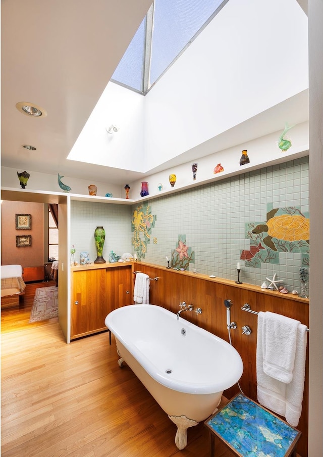 full bath featuring wood finished floors, a soaking tub, a skylight, and ensuite bathroom