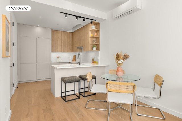 kitchen featuring sink, a wall mounted AC, track lighting, white cabinets, and kitchen peninsula