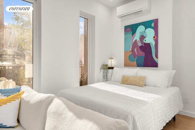 bedroom featuring wood-type flooring and a wall unit AC