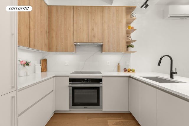 kitchen with sink, white cabinets, black electric stovetop, stainless steel oven, and light hardwood / wood-style flooring