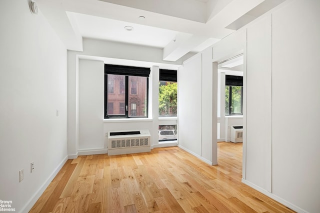 unfurnished living room featuring heating unit, a wall mounted air conditioner, and light hardwood / wood-style floors