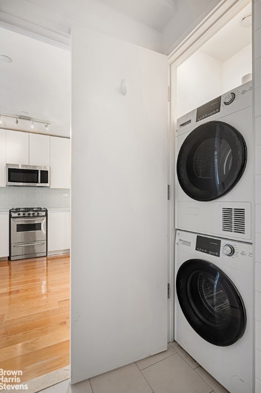 laundry room with stacked washer and clothes dryer and light tile patterned floors