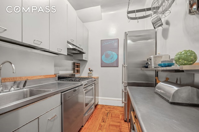 kitchen with under cabinet range hood, stainless steel countertops, a sink, white cabinetry, and appliances with stainless steel finishes