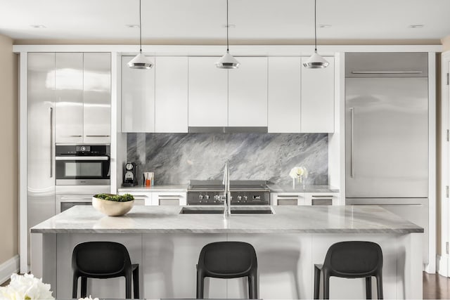 kitchen with appliances with stainless steel finishes, modern cabinets, white cabinets, a kitchen breakfast bar, and backsplash