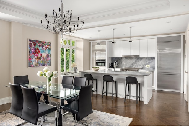 dining space with a chandelier, ornamental molding, and a raised ceiling