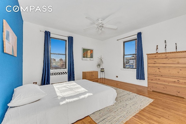 bedroom featuring multiple windows, hardwood / wood-style flooring, and ceiling fan