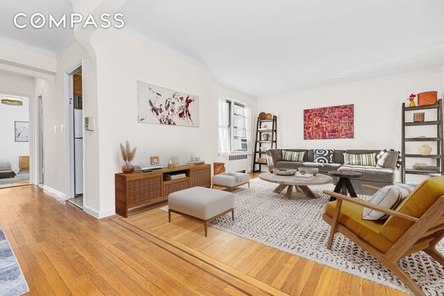 living area featuring light wood-style floors, radiator heating unit, and baseboards