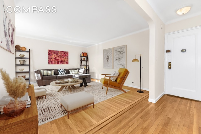 living room with light wood-type flooring, arched walkways, and baseboards