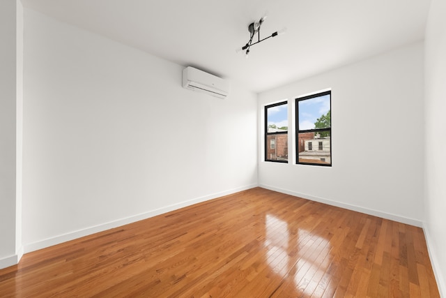 empty room featuring wood-type flooring and an AC wall unit