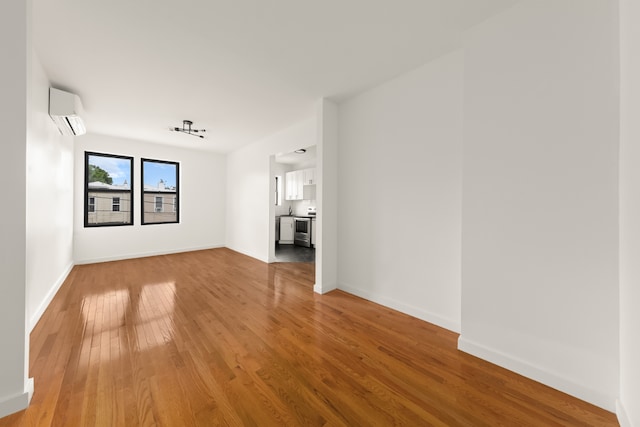 unfurnished living room featuring hardwood / wood-style floors and a wall mounted air conditioner