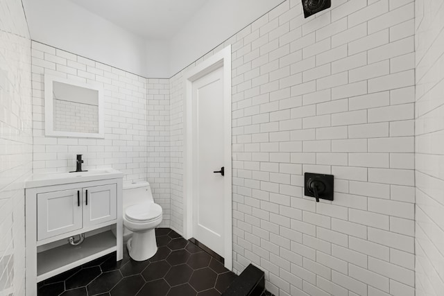 bathroom with tile patterned flooring, vanity, tile walls, and toilet